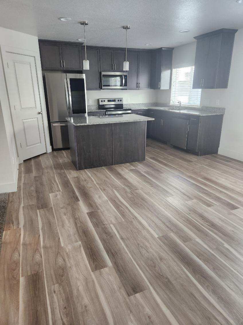 Kitchen with dark cabinets, granite island, and stainless appliances